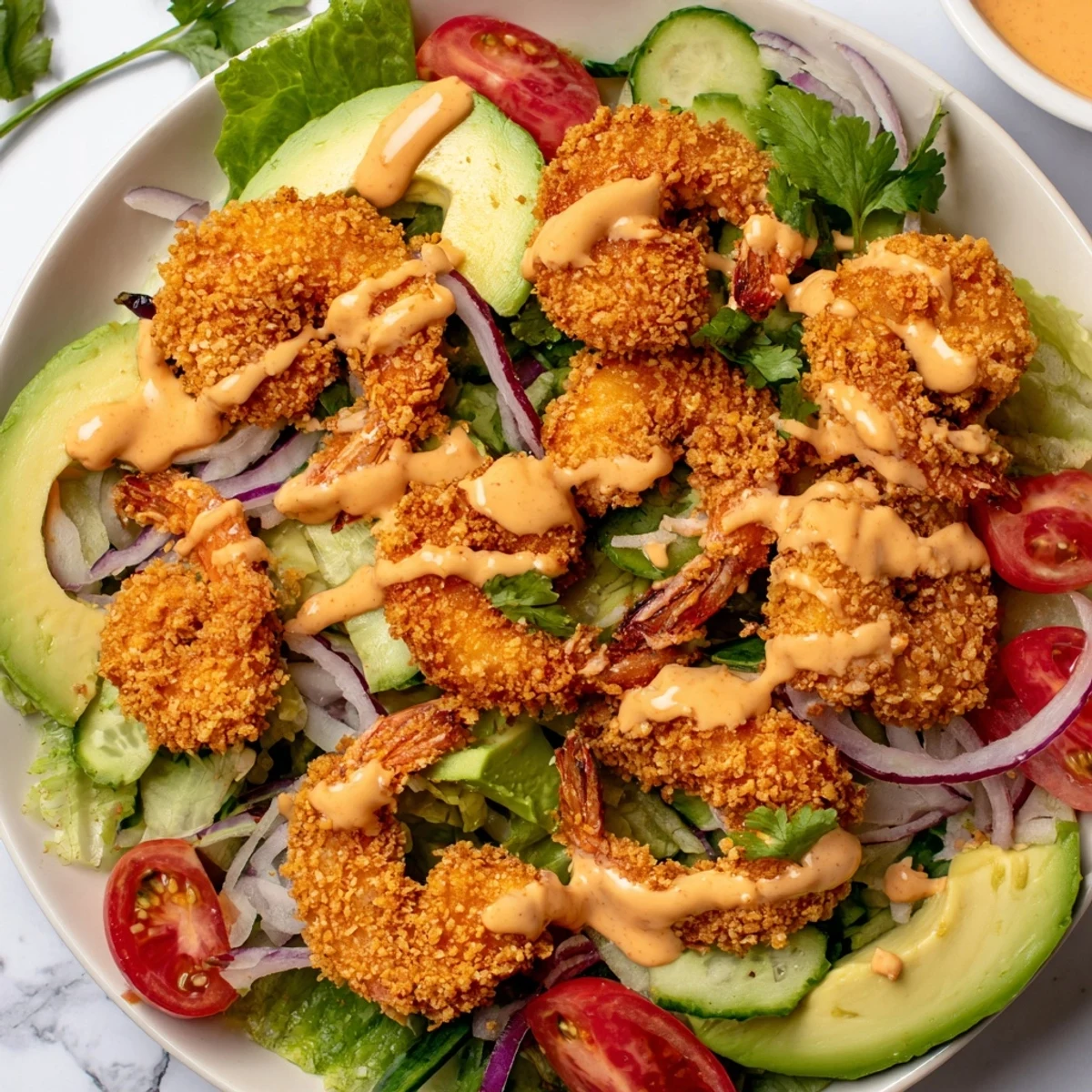 This image shows a beautifully arranged Spicy Crispy Shrimp Salad, finished with a flavorful, creamy sriracha dressing.