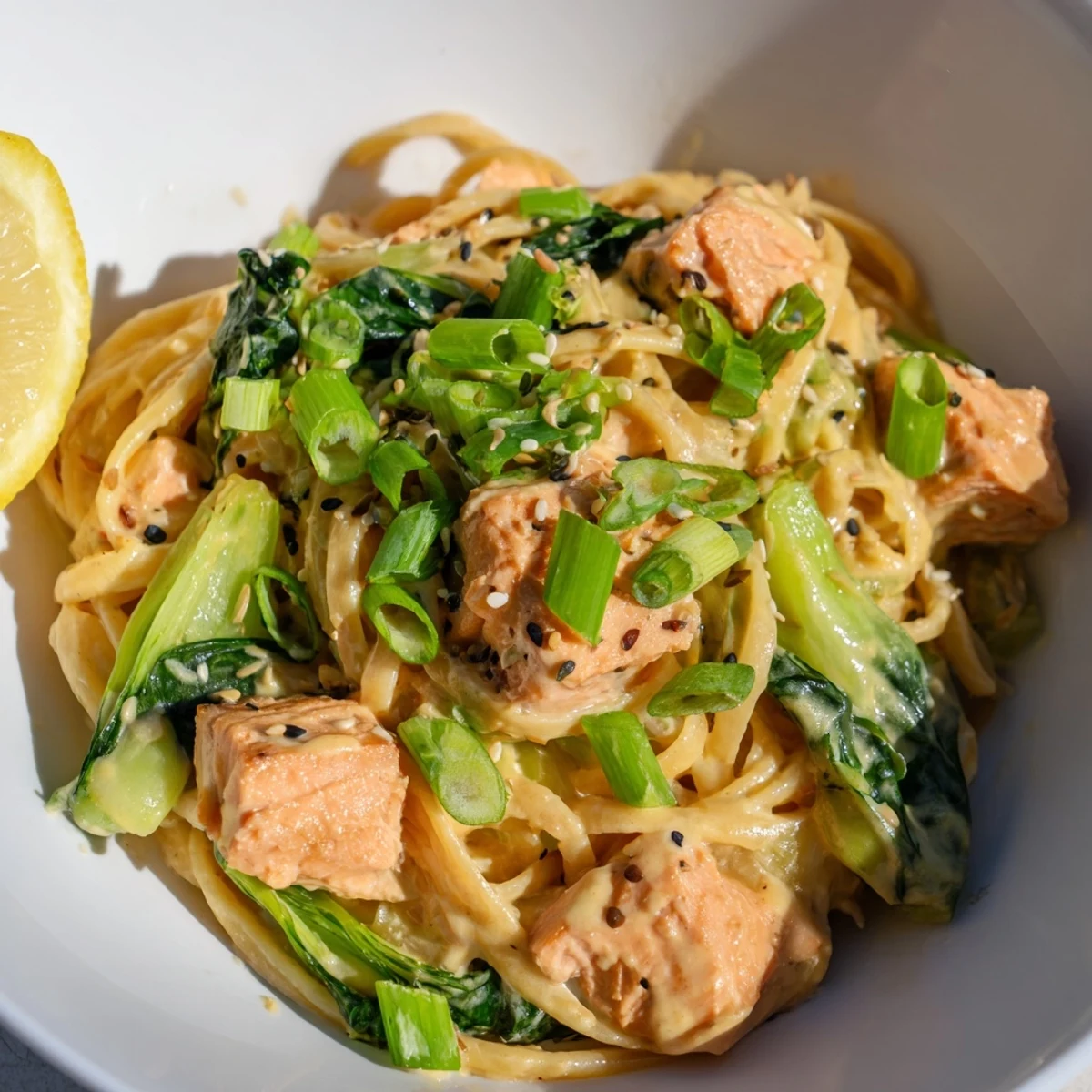 Creamy miso butter salmon pasta, served with vibrant bok choy and fresh scallions, is a satisfying meal.