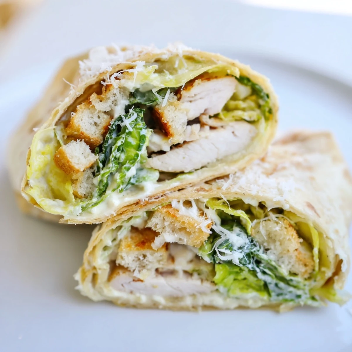 Grilled chicken slices and crisp romaine lettuce with creamy Caesar dressing in a soft flour tortilla for a handheld wrap.