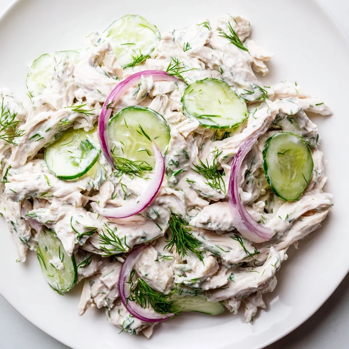 A bowl of Creamy Cucumber Chicken Salad featuring tender shredded chicken, crisp cucumber slices, and fresh dill garnish.