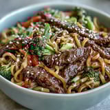 Close-up of silky rice noodles coated in glossy soy-brown sugar sauce with tender flank steak and crisp bell peppers.