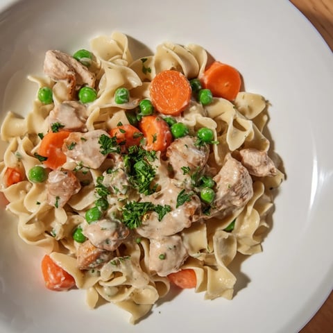 A close-up of creamy chicken and egg noodles, a comforting home-cooked meal with herbs.