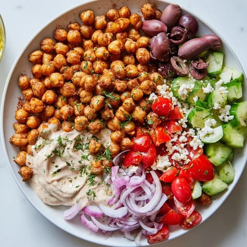 A healthy Mediterranean Chickpea Bowl, featuring roasted chickpeas, a creamy dressing, and vibrant veggies.