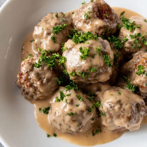 A close-up of hearty Swedish Meatballs, bathed in a rich, savory gravy, ready to eat.