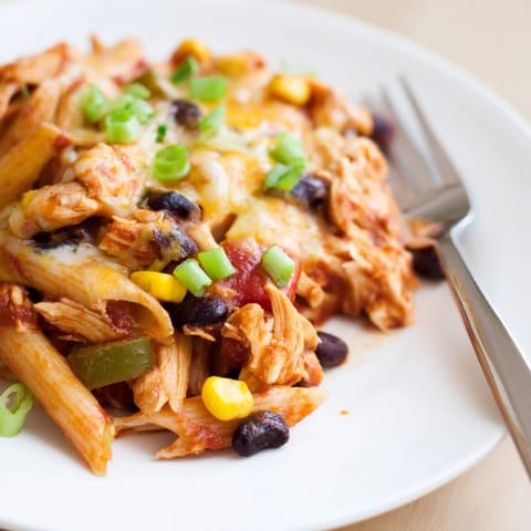 A skillet of Chicken Enchilada Pasta is topped with fresh cilantro and diced avocado, ready for a weeknight dinner.