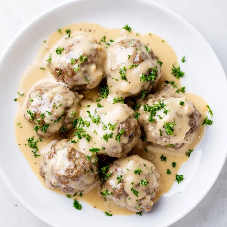 Golden-brown Swedish Meatballs, presented with mashed potatoes and lingonberry jam, a comforting meal.
