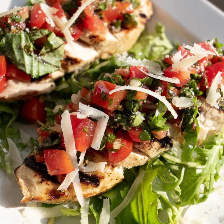 Freshly chopped tomatoes and basil crown the grilled chicken for this vibrant bruschetta chicken salad served on a bed of greens.