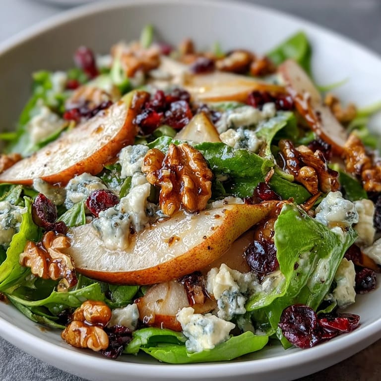 A close-up of a delicious Pear Gorgonzola Salad featuring juicy pears, tangy cheese, and a glossy honey-balsamic dressing glaze.