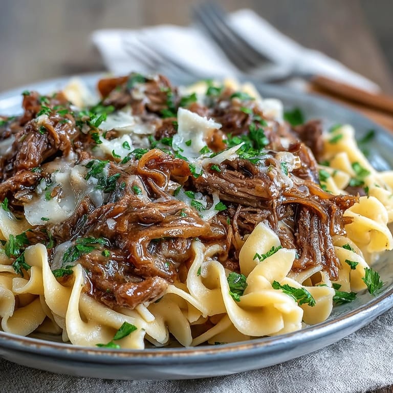Slow-cooked shredded beef and sweet onions over wide egg noodles make this Crockpot French Onion Pot Roast Pasta a comforting weeknight meal.