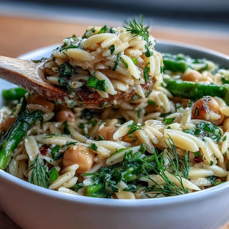 Creamy orzo pasta simmered with chickpeas, asparagus, and zucchini in a zesty lemon herb broth, perfect for a healthy vegetarian dinner.  